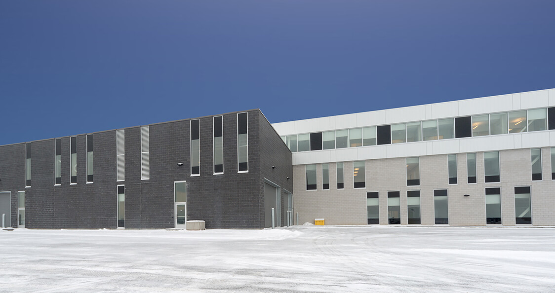 Bâtiment institutionnel en béton avec passerelle vitrée aérienne et esplanade extérieure